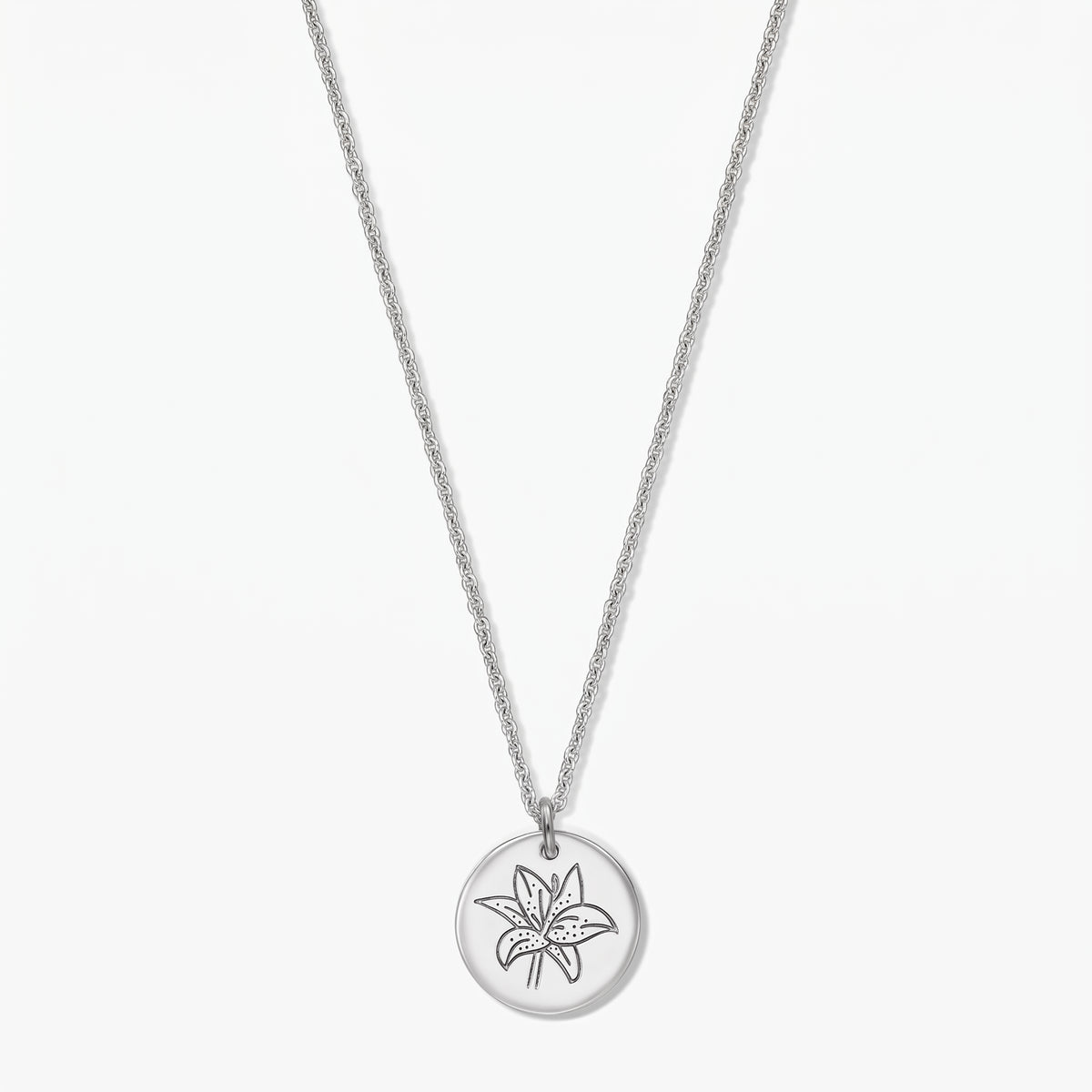 Collana in argento sterling con fiore del mese di nascita, pendente a disco rotondo inciso con un giglio (maggio), su sfondo bianco.