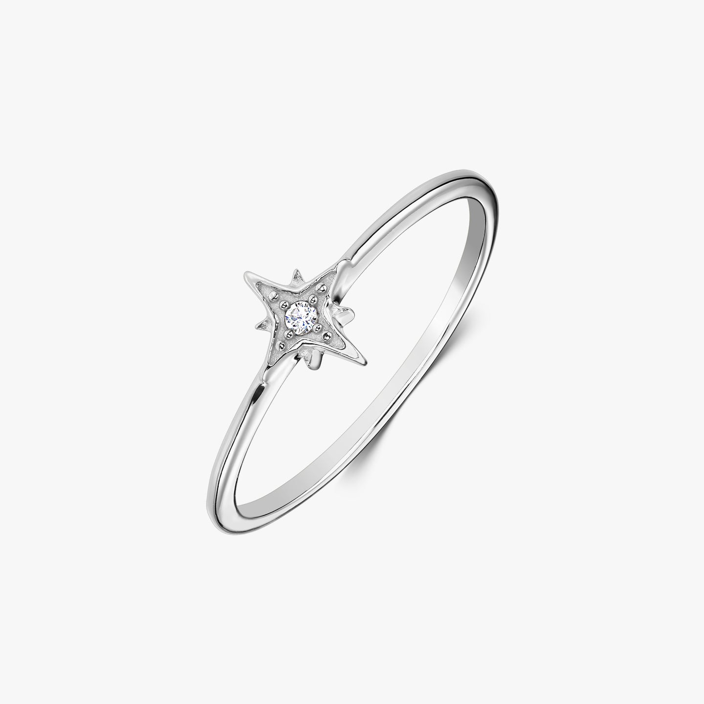 Anello delicato in argento sterling con montatura a forma di stella che incastona una zirconia bianca, fotografato su sfondo bianco.