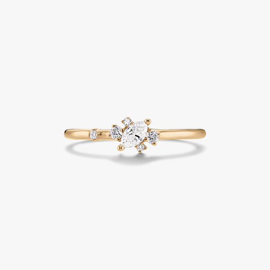 Anello sottile in oro giallo 14K con diamante centrale taglio marquise e piccoli diamanti rotondi d'accento su sfondo bianco.