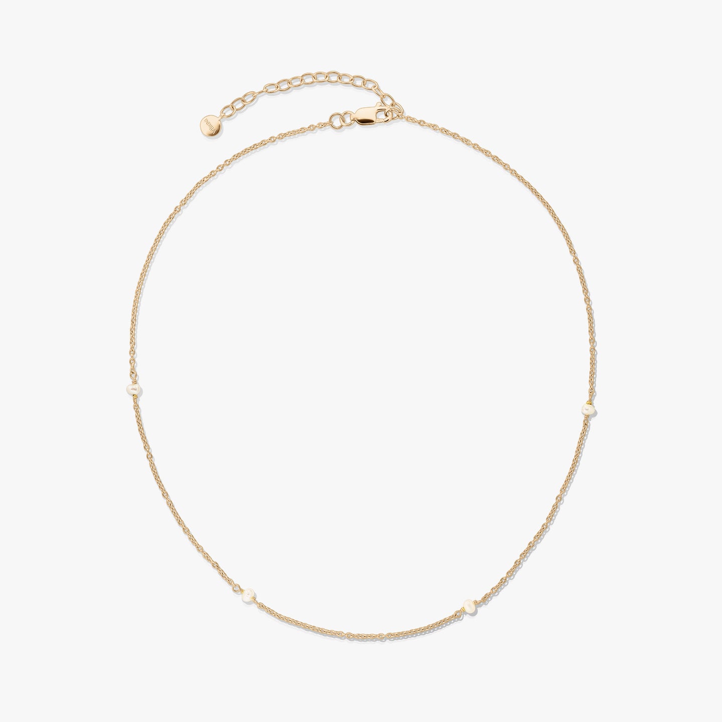 Collana in argento 925 placcata in oro, delicata, con piccole perle naturali e prolunga regolabile con chiusura a moschettone su sfondo bianco.