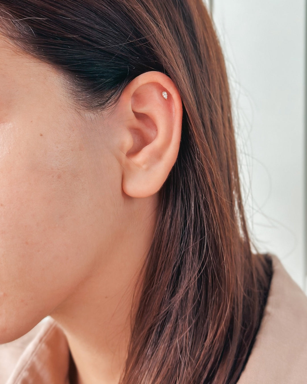 Primo piano di un orecchio con un piccolo orecchino a perno