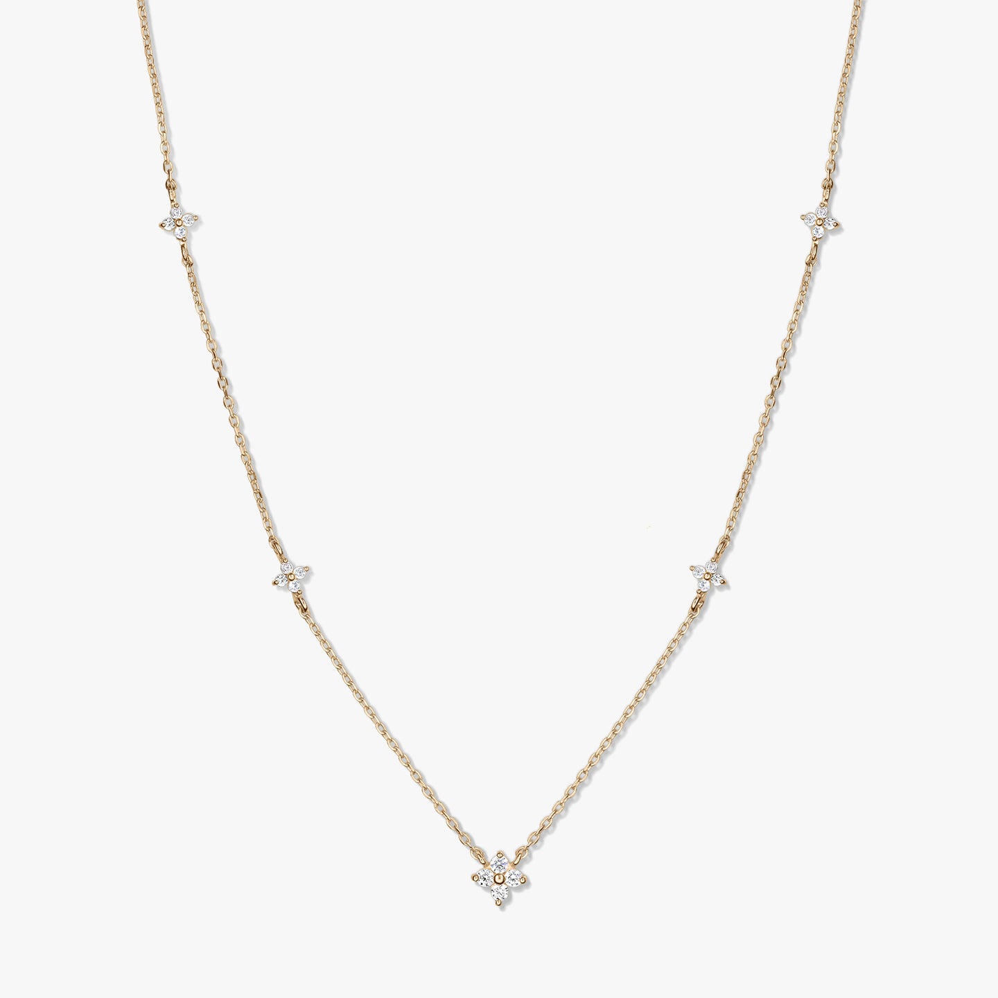 Collana a stazioni in oro giallo 14K con piccoli motivi a quadrifoglio in zirconia bianca su una catena sottile, fotografata su sfondo bianco.