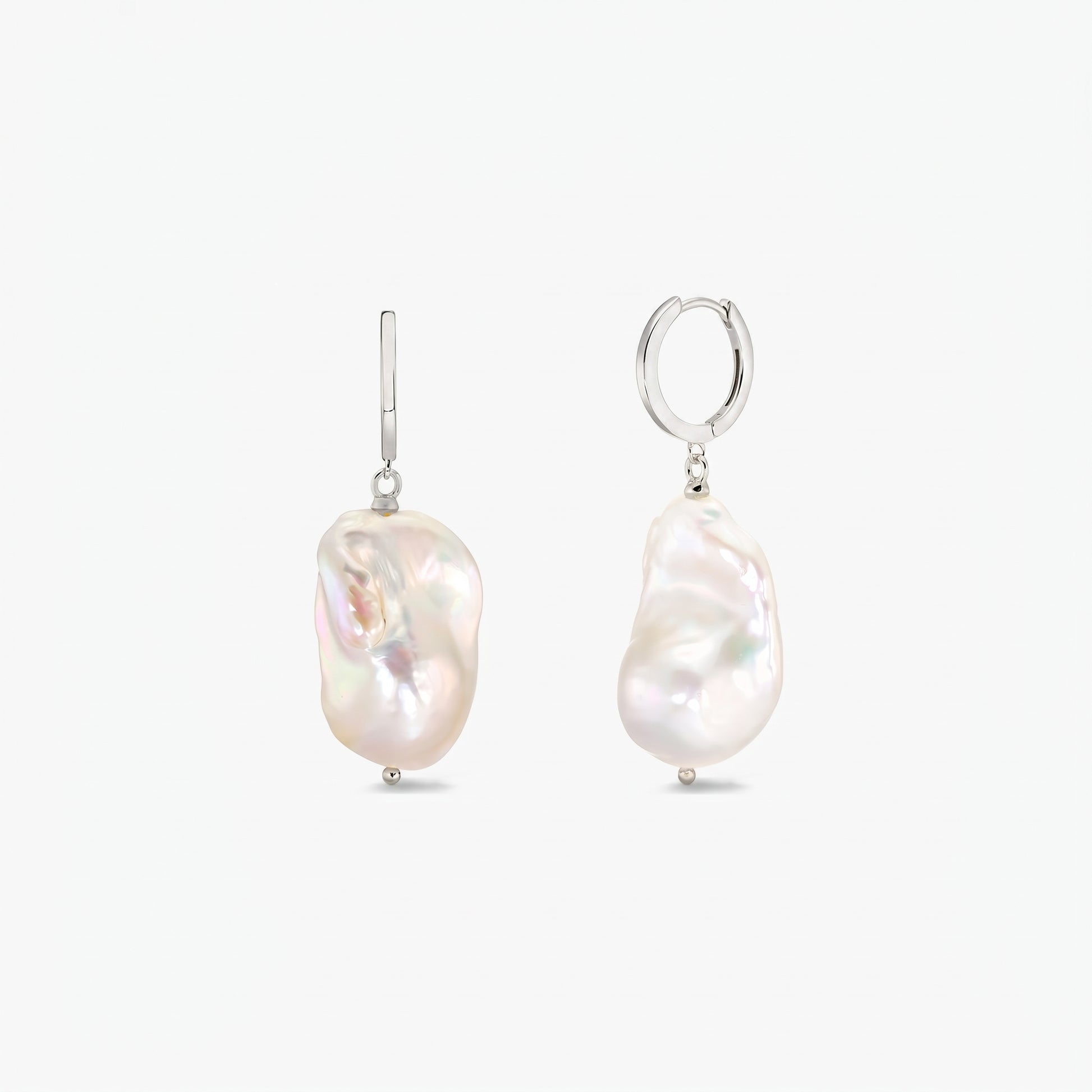 Paio di orecchini a cerchio in argento sterling con grandi perle barocche bianche irregolari su sfondo bianco pulito.
