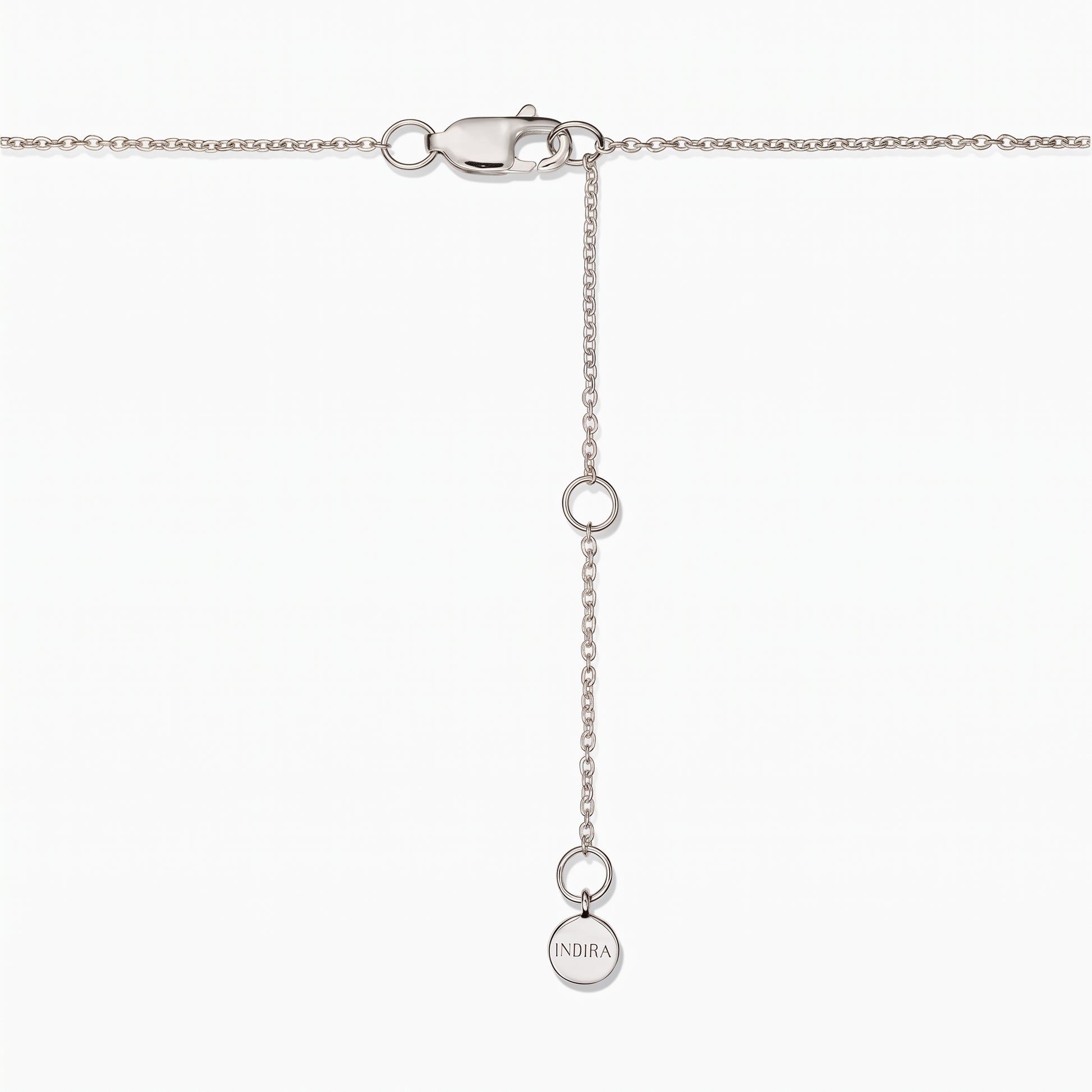 Primo piano della chiusura di una collana in argento sterling con catenella di prolunga regolabile e una piccola targhetta rotonda Indira su sfondo bianco.