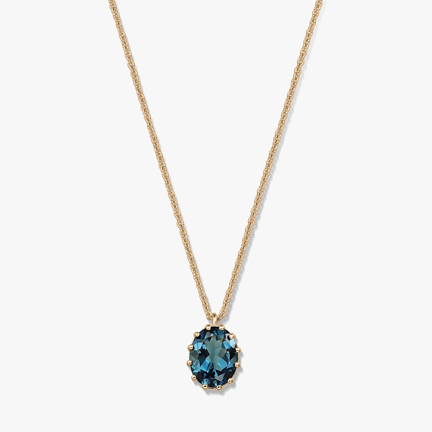 Delicata collana in argento sterling placcato oro con pendente ovale in topazio London Blue su sfondo bianco.