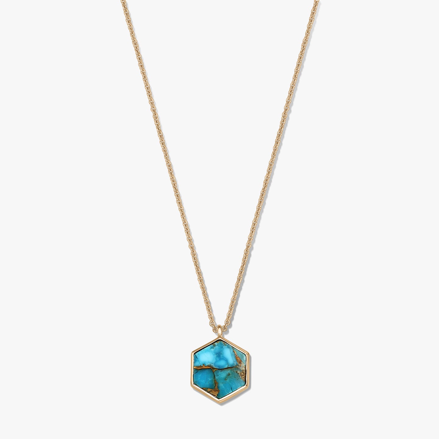 Collana in argento sterling placcato oro con pendente esagonale in rame color turchese, su sfondo bianco.