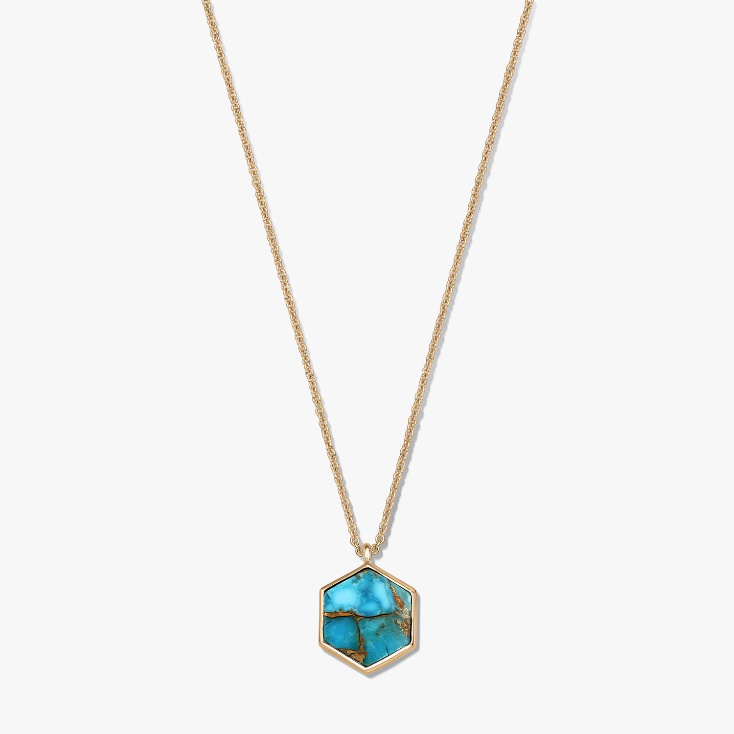 Collana in argento sterling placcato oro con pendente esagonale in rame color turchese, su sfondo bianco.