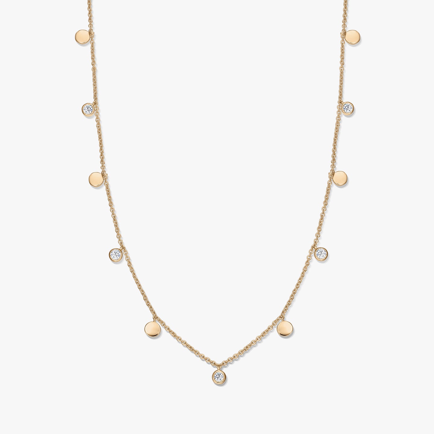 Collana a stazioni in argento sterling placcato oro con piccoli ciondoli a disco lucidi alternati e topazi bianchi incastonati a castone su una catena sottile, fotografata su sfondo bianco.