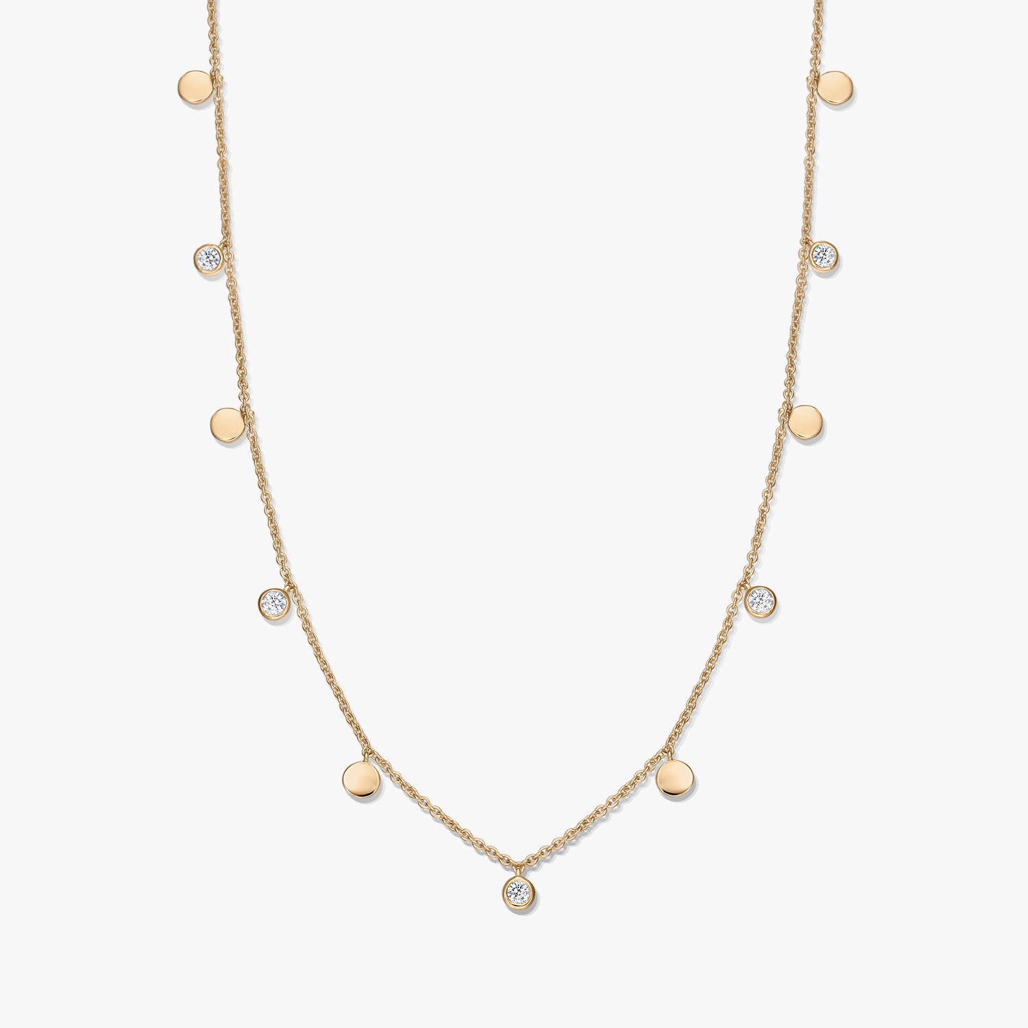 Collana a stazioni in argento sterling placcato oro con piccoli ciondoli a disco lucidi alternati e topazi bianchi incastonati a castone su una catena sottile, fotografata su sfondo bianco.
