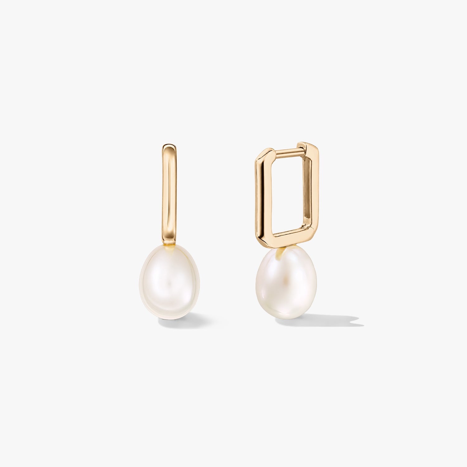 Orecchini huggie in argento sterling placcato oro con pendenti con perle naturali bianche, uno mostrato aperto per evidenziare la chiusura rettangolare, su sfondo bianco.