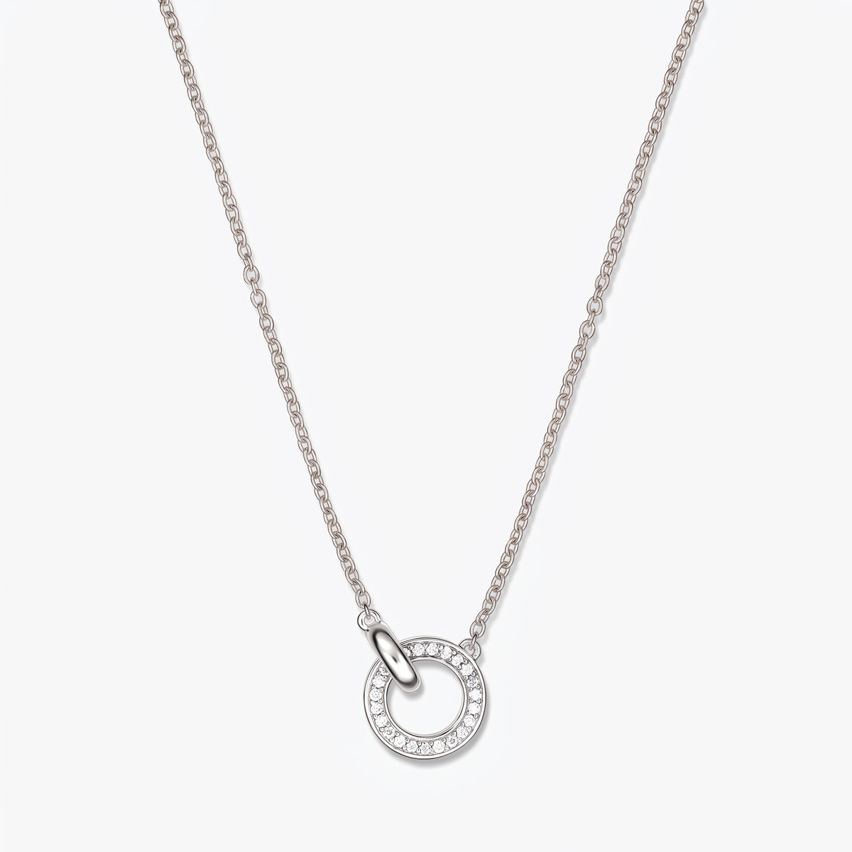 Collana a maglie in argento con pendente a doppio cerchio impreziosito da piccole pietre trasparenti su una sottile catena d'argento, fotografata su sfondo bianco.