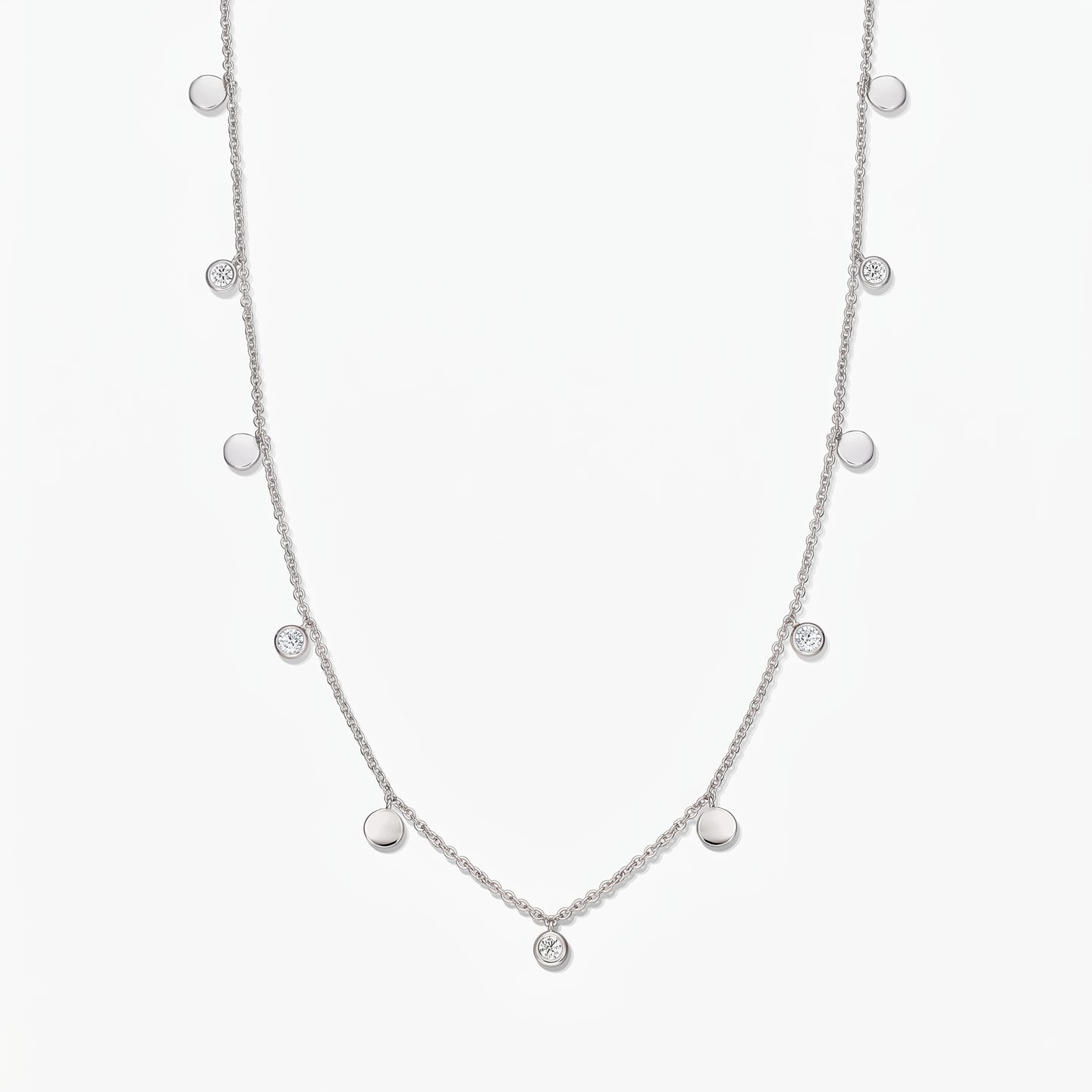 Collana a stazioni in argento sterling Noora con dischetti lucidi alternati e topazi bianchi incastonati a castone, su sfondo bianco.