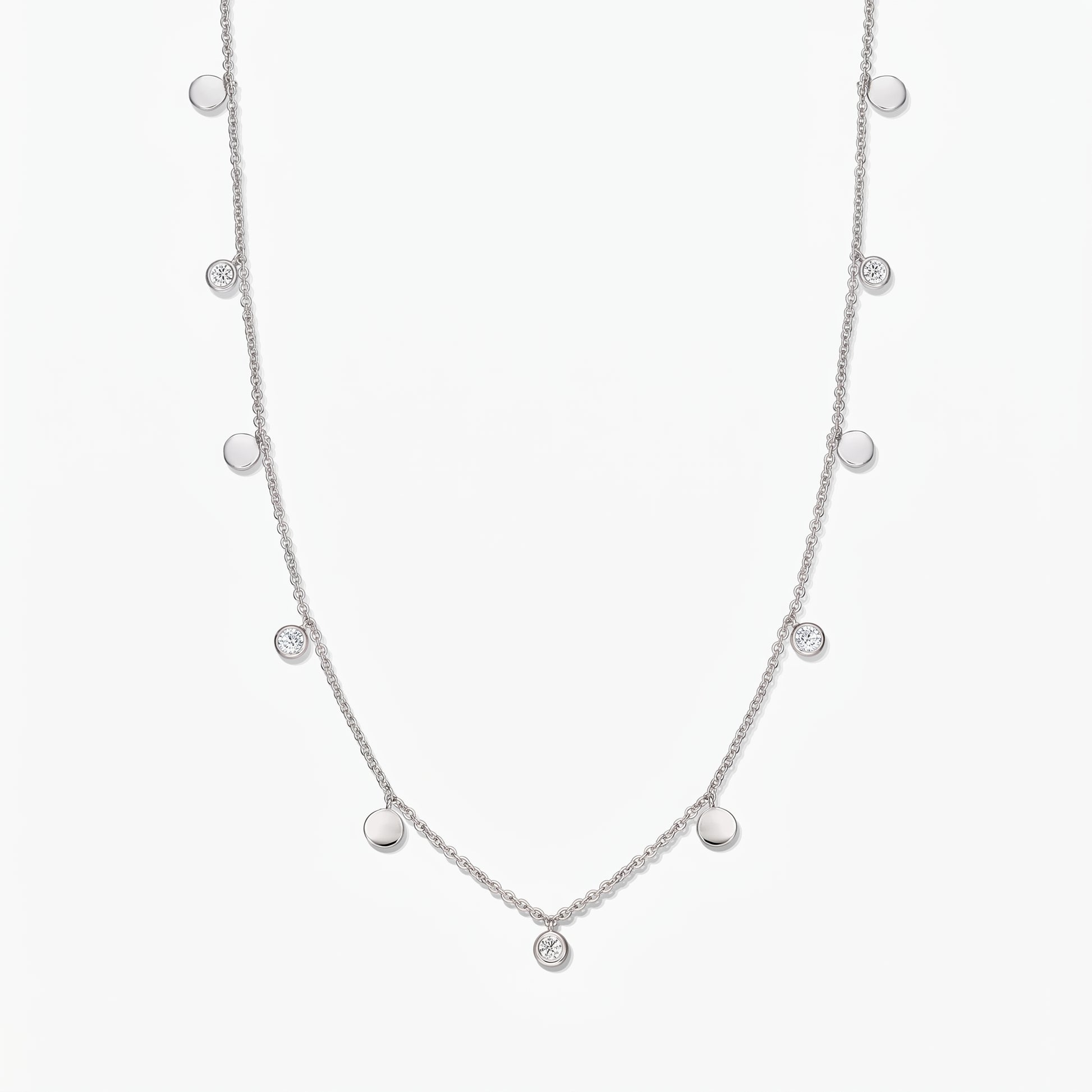 Collana a stazioni in argento sterling Noora con dischetti lucidi alternati e topazi bianchi incastonati a castone, su sfondo bianco.