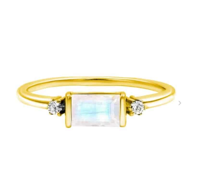 Anello Eva in argento dorato con pietra di luna e zirconi, caratterizzato da una pietra di luna rettangolare e due zirconi su una fascia in argento placcato oro.