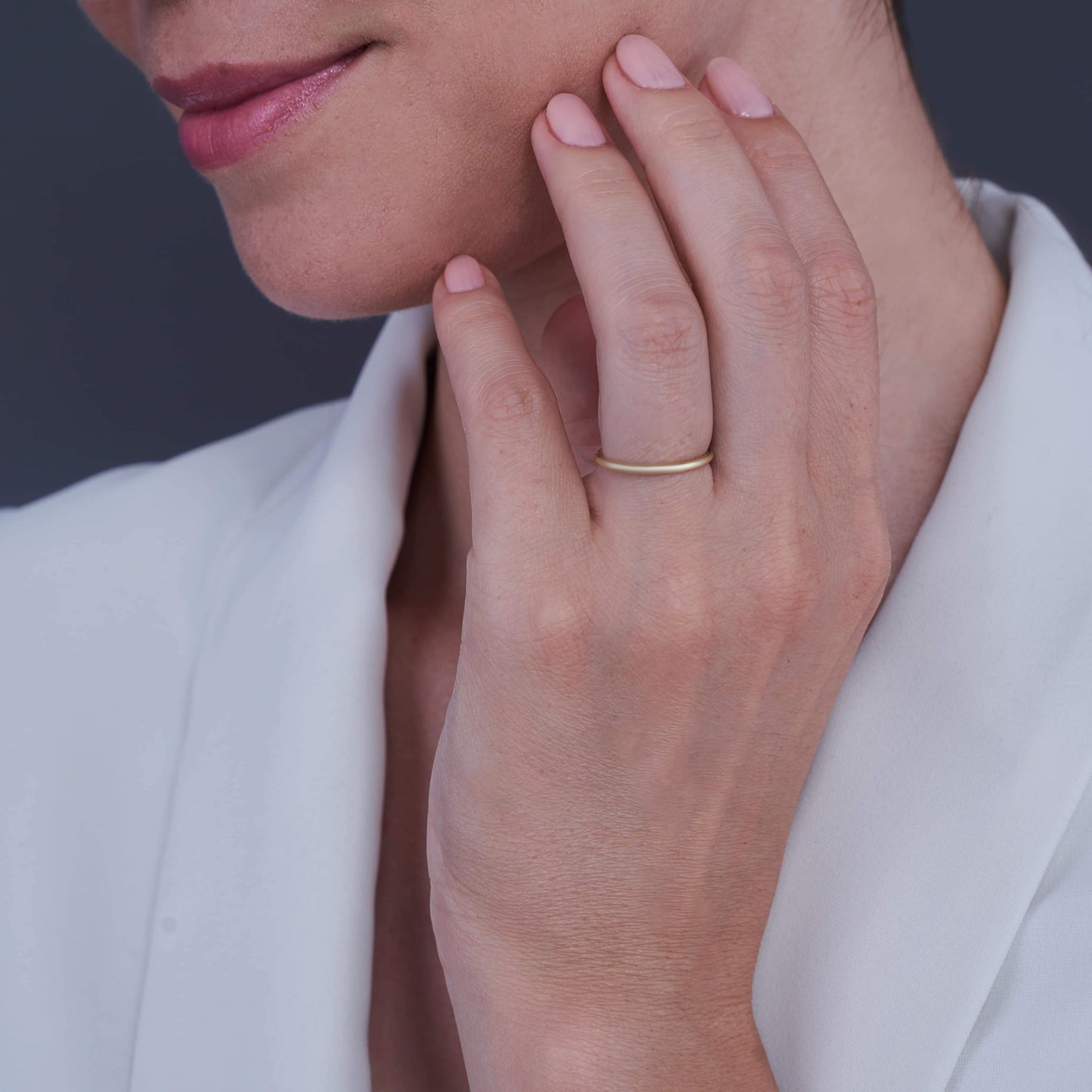 Mano di donna appoggiata al mento con un Sorriso Dolce, indossa un Anello in Argento Placcato Oro Layla al dito medio.
