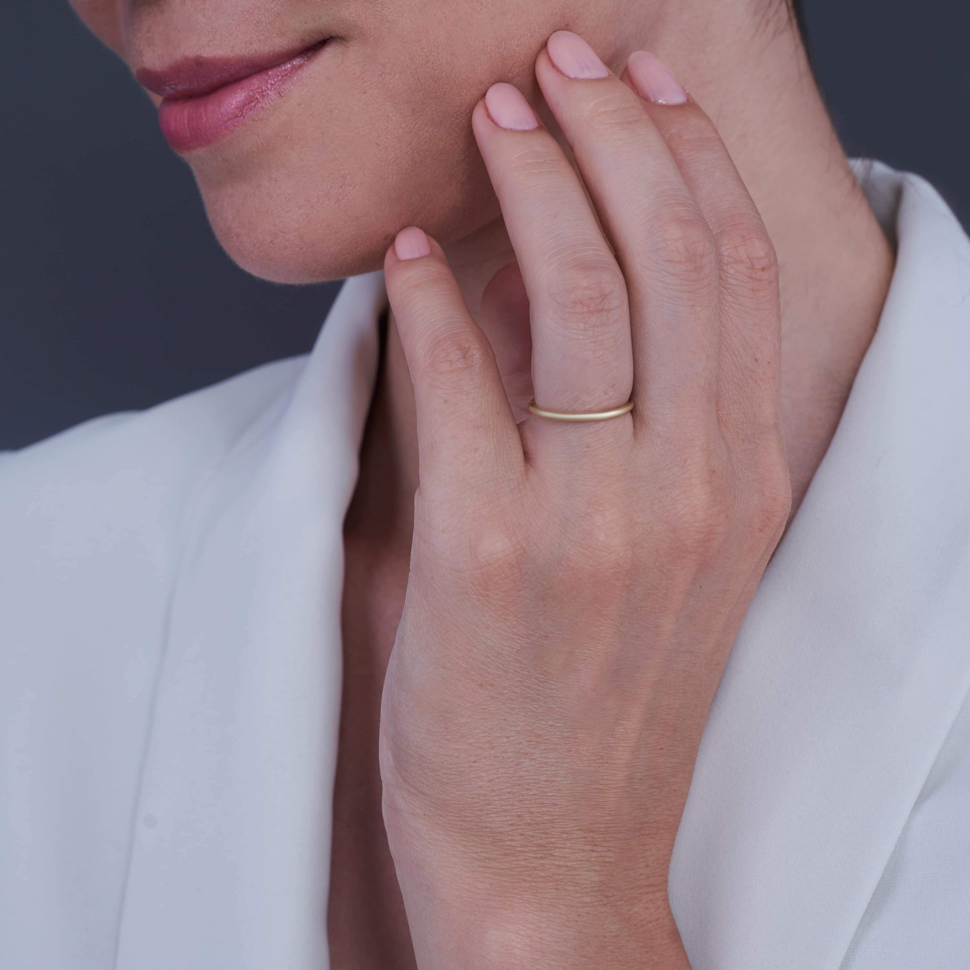 Mano di donna appoggiata al mento con un Sorriso Dolce, indossa un Anello in Argento Placcato Oro Layla al dito medio.