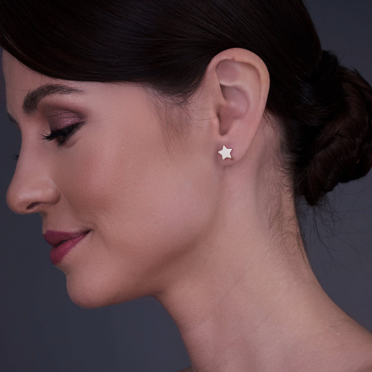 Vista di profilo di una donna che indossa orecchini a forma di stella in oro 14K.