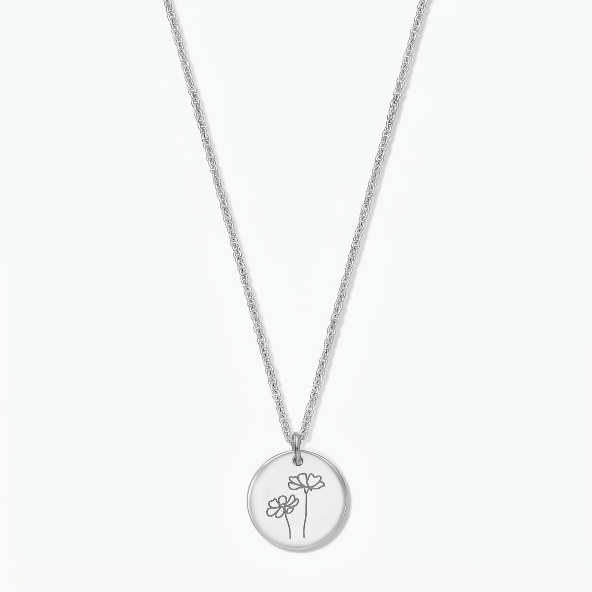 Collana in argento sterling con fiore del mese di ottobre (Cosmos) di Indira, con pendente rotondo a disco inciso con due fiori di Cosmos su una catenina sottile in argento, isolata su sfondo bianco.