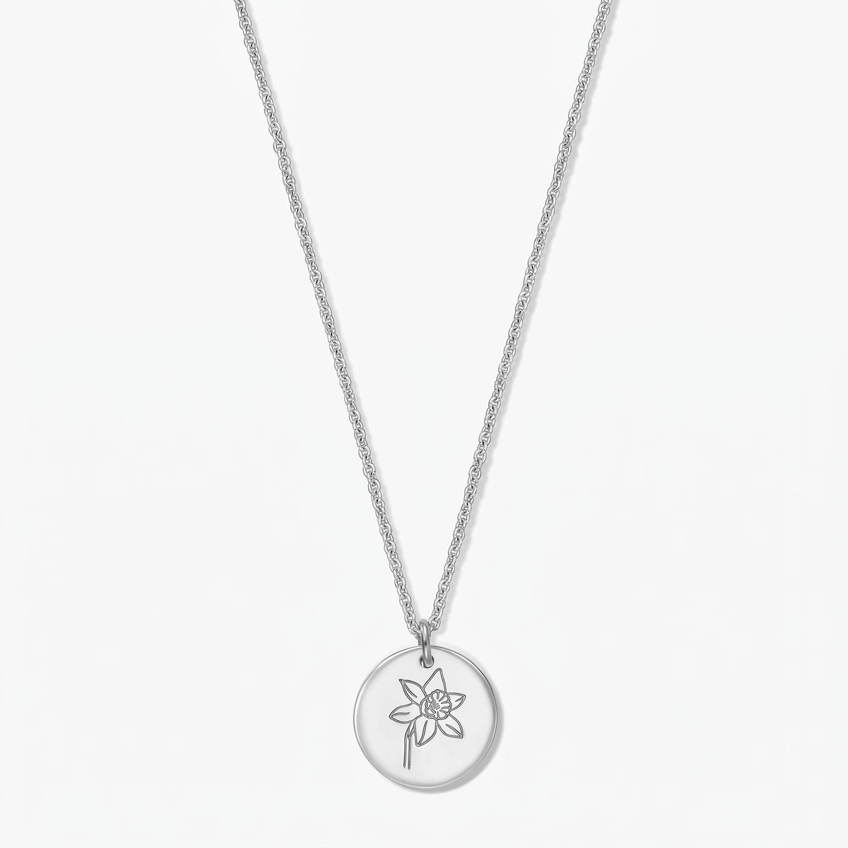 Collana in argento sterling con ciondolo rotondo inciso raffigurante un narciso (fiore di nascita di marzo) su sfondo bianco.
