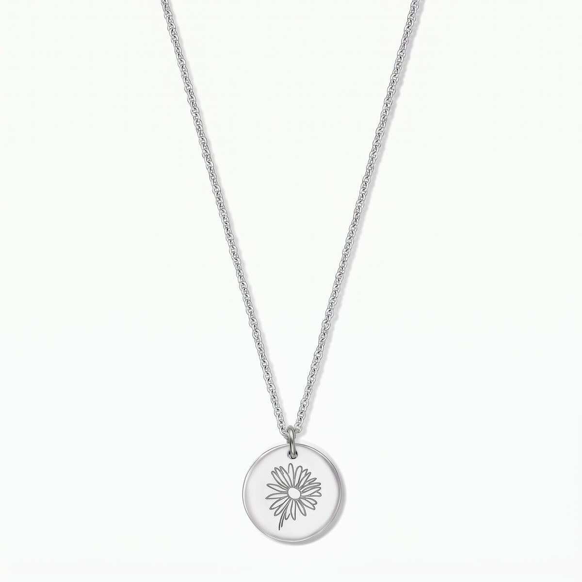 Collana in argento sterling con pendente a disco rotondo inciso con una margherita, fotografata su sfondo bianco.