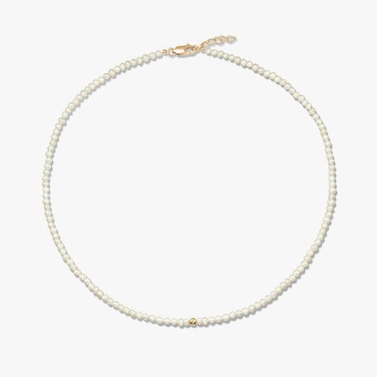 Immagine quadrata del prodotto: collana delicata di perle naturali con piccolo dettaglio a sfera in oro giallo 14K e chiusura a moschettone in oro giallo con corta prolunga, su sfondo bianco.
