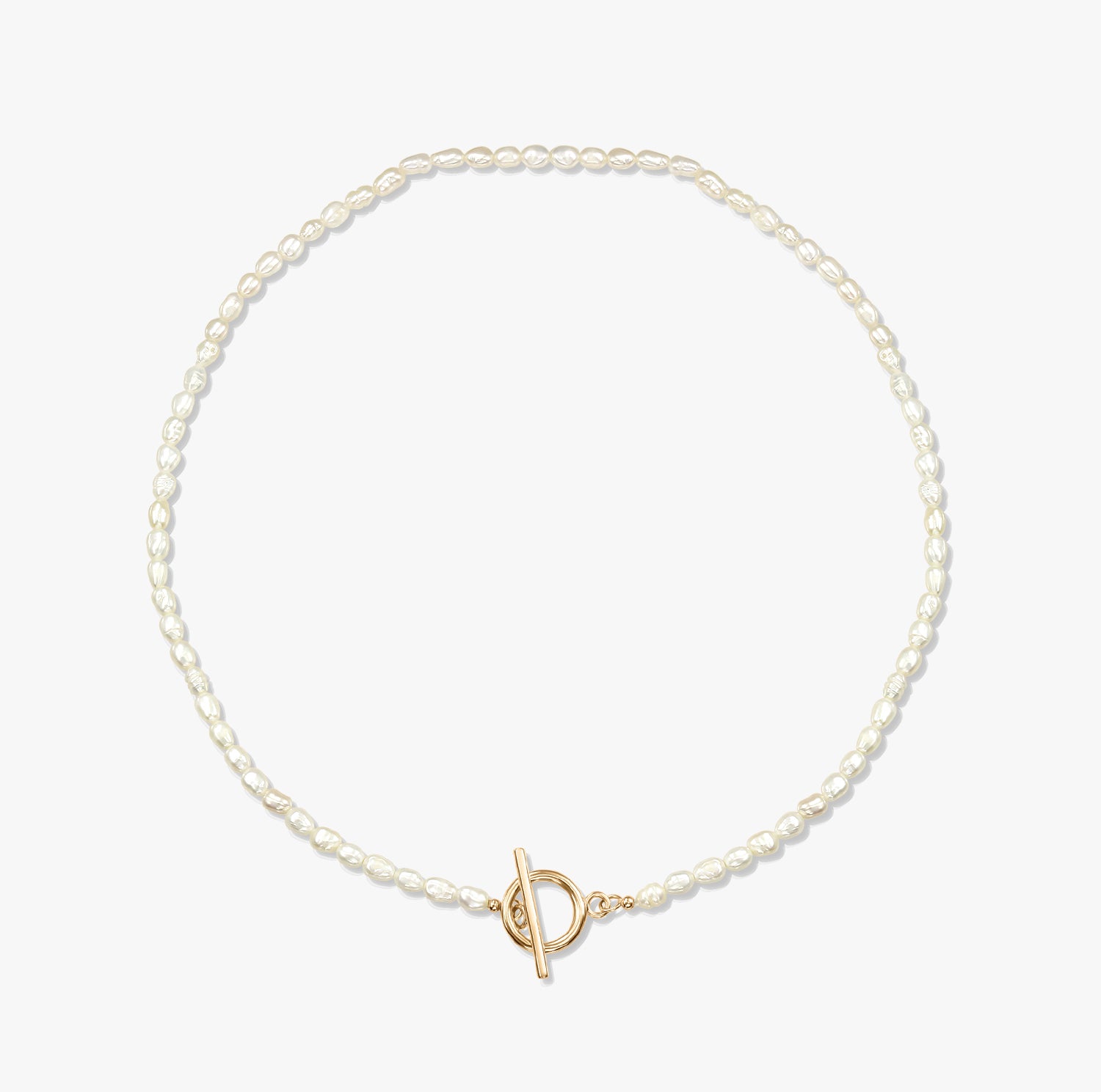 Collana minimalista con perla e chiusura a T in oro su sfondo bianco.