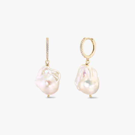 Coppia di orecchini a cerchio huggie in argento 925 placcato oro con pavé di zirconi e grandi perle barocche bianche di acqua dolce su sfondo bianco.