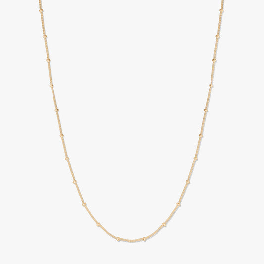 Collana a catena in argento placcato oro con perline, presentata su sfondo bianco, che forma una delicata U con piccole stazioni di perline lungo la catena.