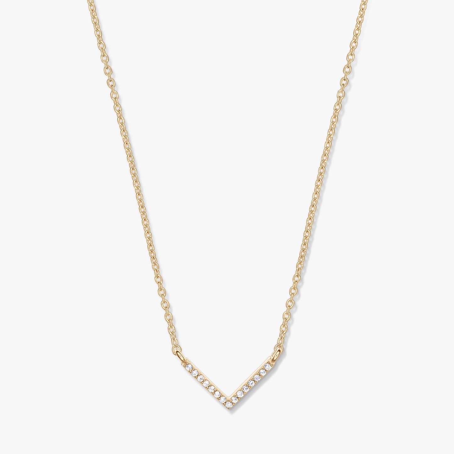 Collana dorata con pendente a forma di V tempestato di zirconi su catena delicata, fotografata su sfondo bianco.