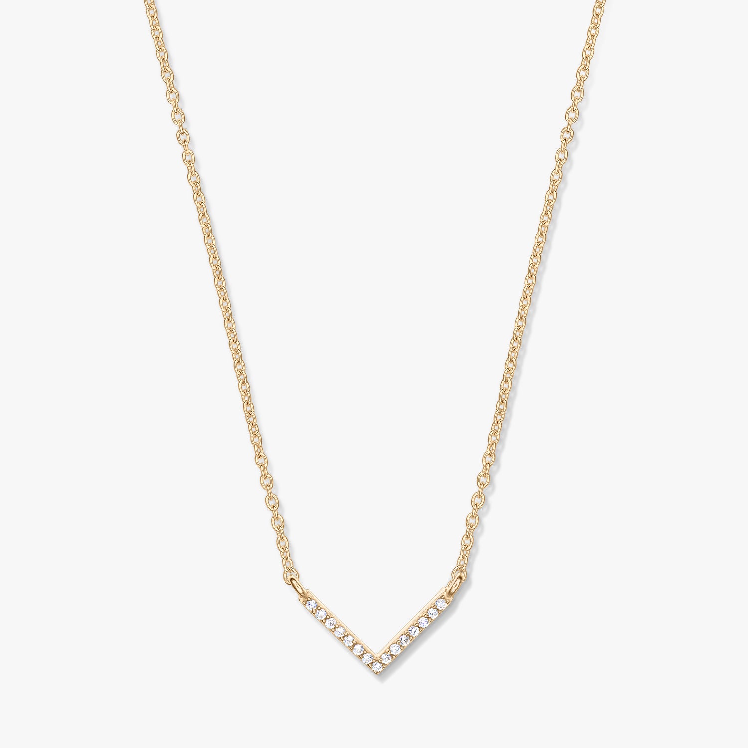 Collana dorata con pendente a forma di V tempestato di zirconi su catena delicata, fotografata su sfondo bianco.