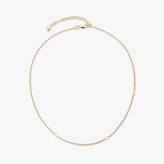 Collana in argento 925 placcata in oro, delicata, con piccole perle naturali e prolunga regolabile con chiusura a moschettone su sfondo bianco.