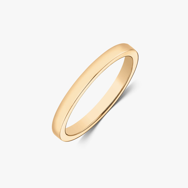 Scatto in studio angolato di un anello a fascia sottile in oro giallo 14k lucido su sfondo bianco.