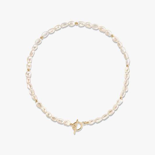 Foto in studio di una collana di perle naturali con piccole perline distanziatrici dorate e chiusura a T in tonalità oro, disposta a cerchio su sfondo bianco.