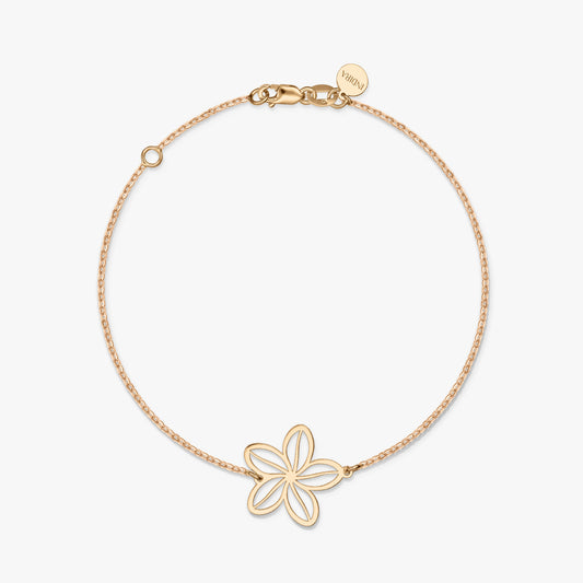 Un braccialetto minimalista in oro con un delicato ciondolo a forma di fiore su uno sfondo bianco solido.