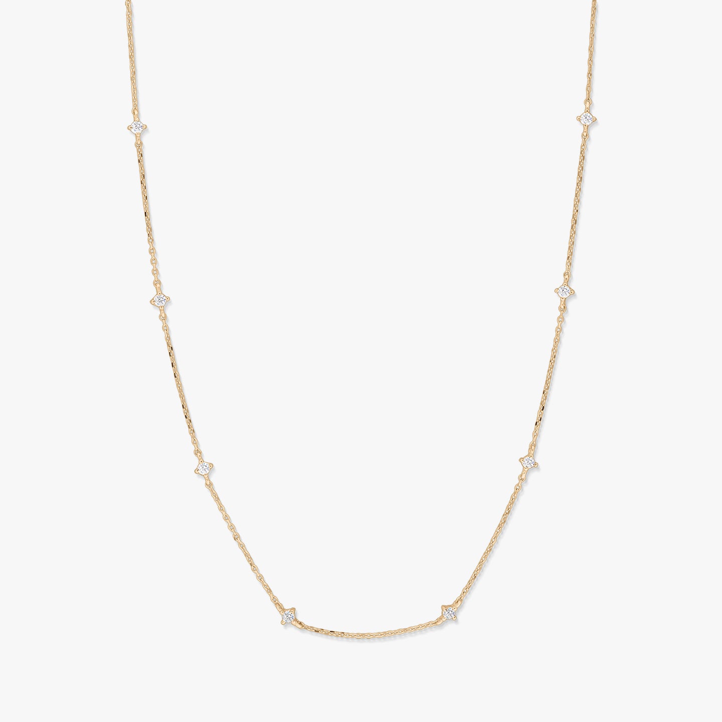 Collana station in oro giallo 14K con piccoli accenti di zirconi bianchi a forma di stella raggiante, distanziati lungo una catena sottile, fotografata su sfondo bianco.