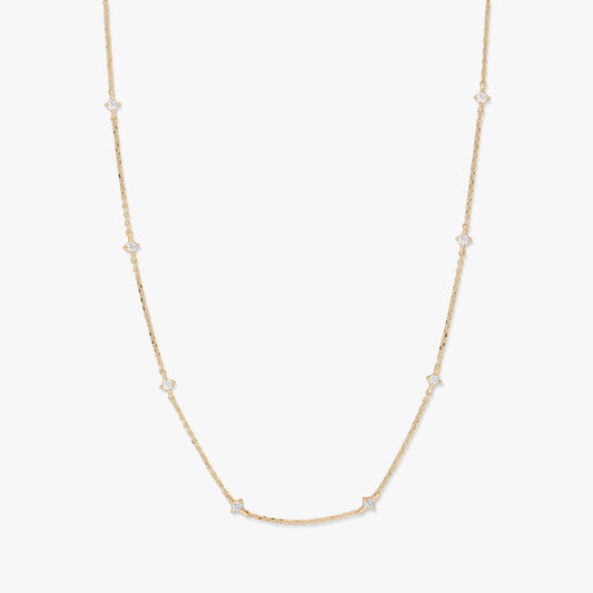 Collana station in oro giallo 14K con piccoli accenti di zirconi bianchi a forma di stella raggiante, distanziati lungo una catena sottile, fotografata su sfondo bianco.