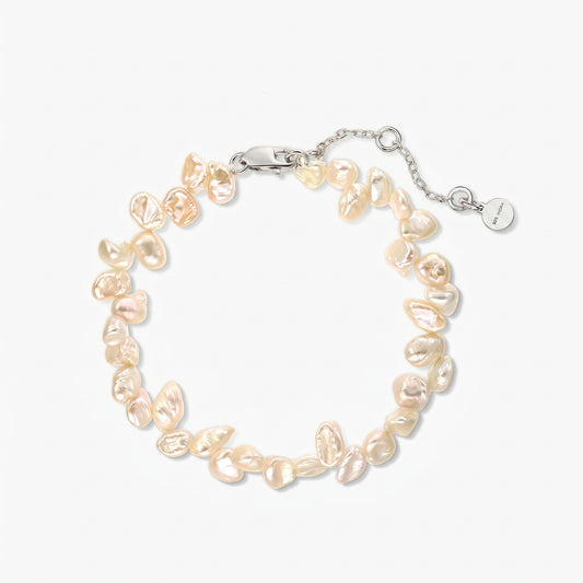 Foto in studio quadrata di un elegante bracciale in argento placcato rodio, infilato con perle keshi rosa d’acqua dolce irregolari, disposto a cerchio su sfondo bianco, con catenina regolabile e chiusura a moschettone.