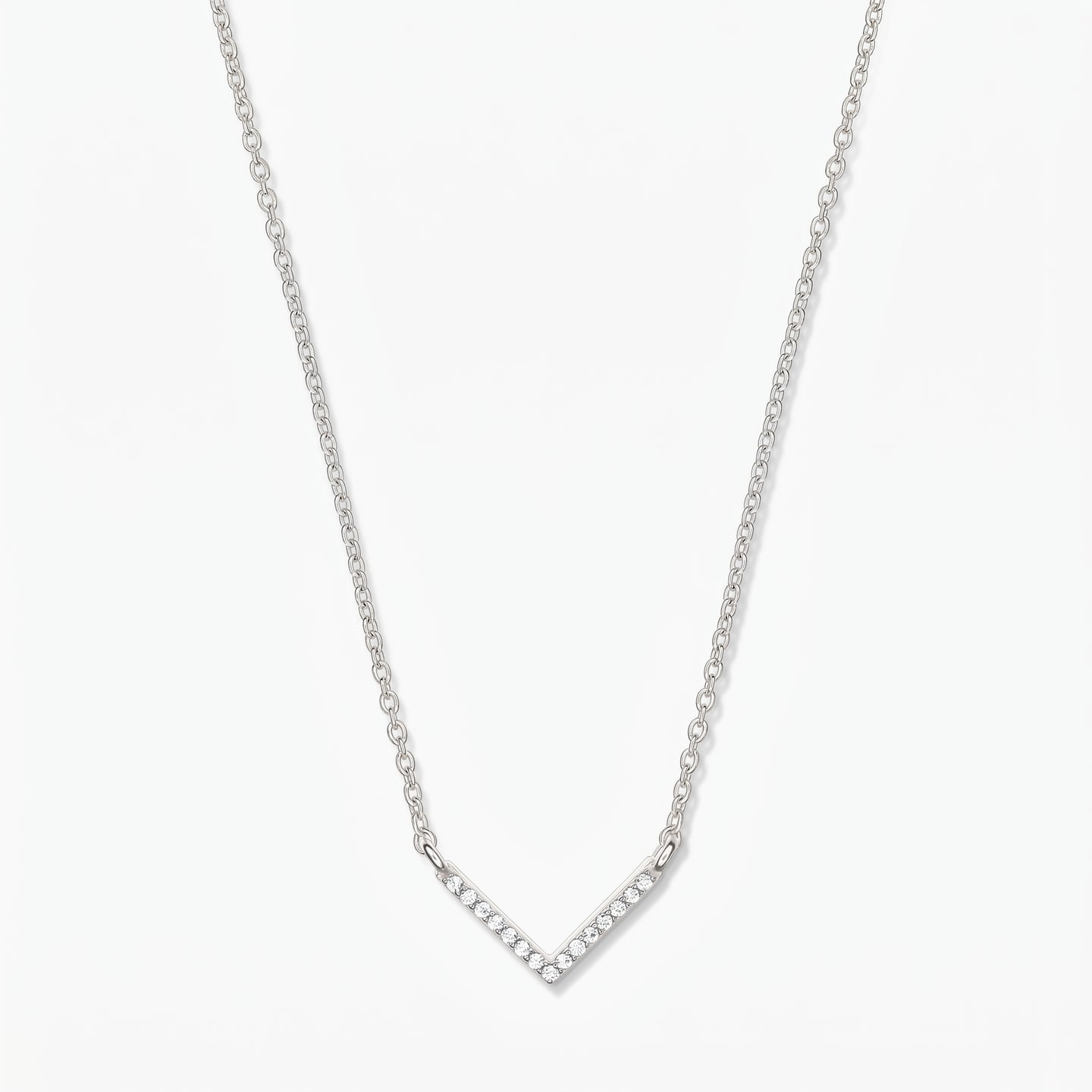 Collana a V in argento con zirconi, catena sottile e ciondolo chevron pavé su sfondo bianco.