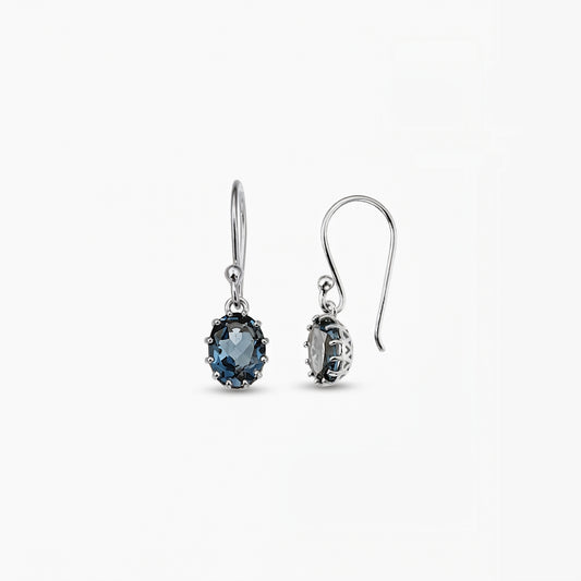 Orecchini pendenti in argento sterling con gemme ovali di topazio London Blue su sfondo bianco.