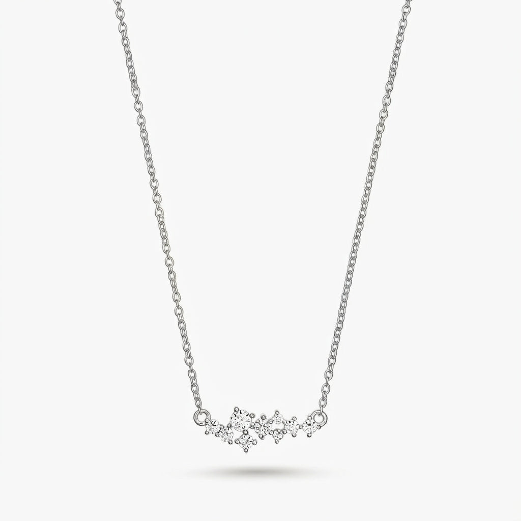 Delicata collana in argento a tema costellazione con piccole pietre trasparenti su una catenina sottile, isolata su sfondo bianco.
