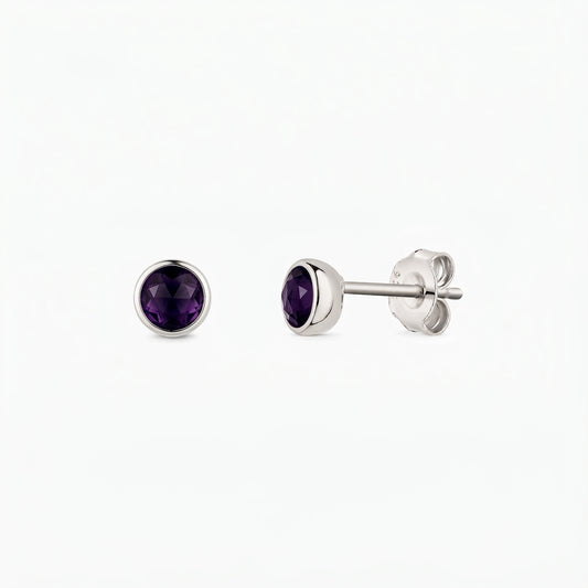 Paio di orecchini a perno in argento 925 con pietre di ametista rotonde sfaccettate, incastonate a castone, mostrati frontalmente e di lato su sfondo bianco.