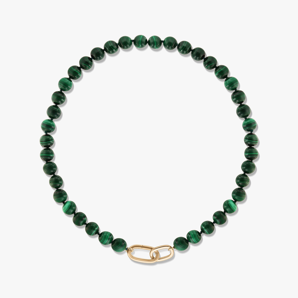 Collana a perline di malachite verde con chiusura a clip di carta in argento sterling placcato oro su sfondo bianco.