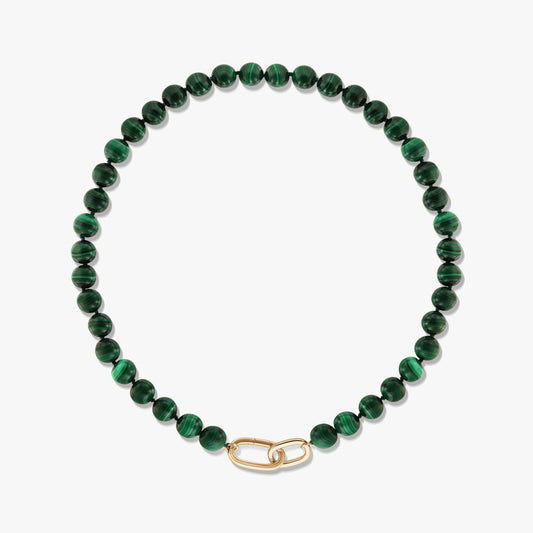 Collana a perline di malachite verde con chiusura a clip di carta in argento sterling placcato oro su sfondo bianco.
