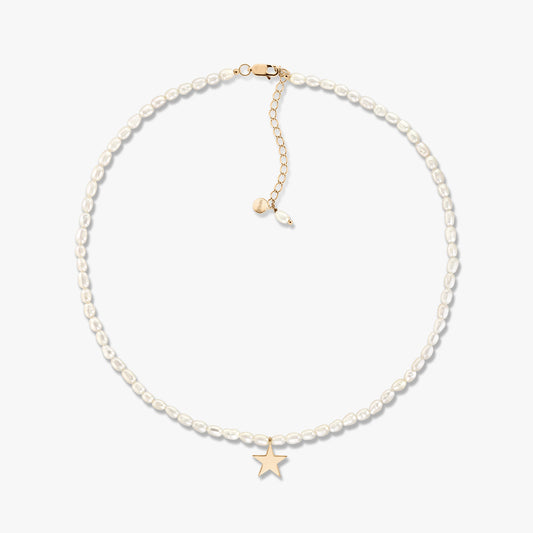 Delicato collier con perle coltivate e piccola stella in oro, con allungatore regolabile in oro, mostrato su sfondo bianco.