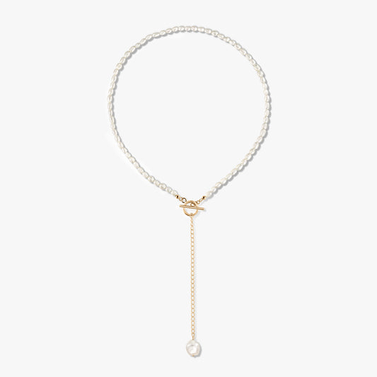 Collana Jacqueline in argento sterling placcato oro 14K con perla, chiusura a barilotto frontale e catena a goccia dorata terminante con una singola perla, su sfondo bianco.