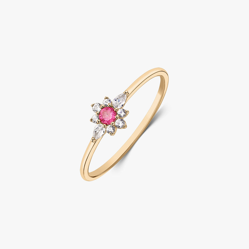 Anello in oro giallo 14k con una tormalina rosa centrale e alone floreale di zaffiri bianchi su sfondo bianco.