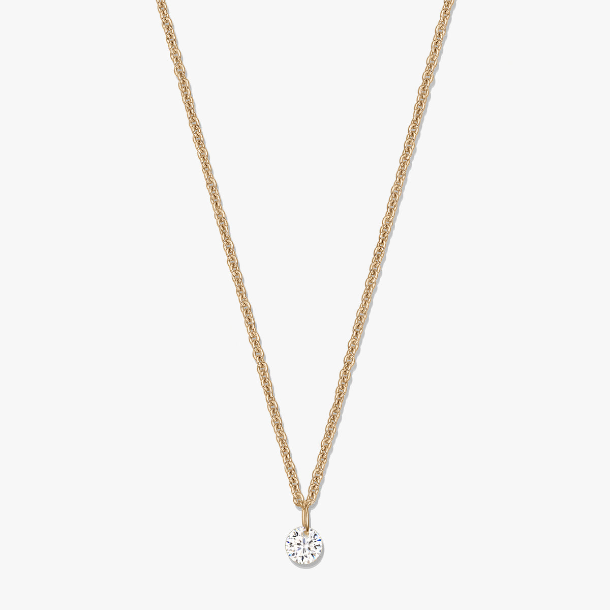 Collana in argento color oro con ciondolo solitario rotondo in zircone trasparente su sfondo bianco.