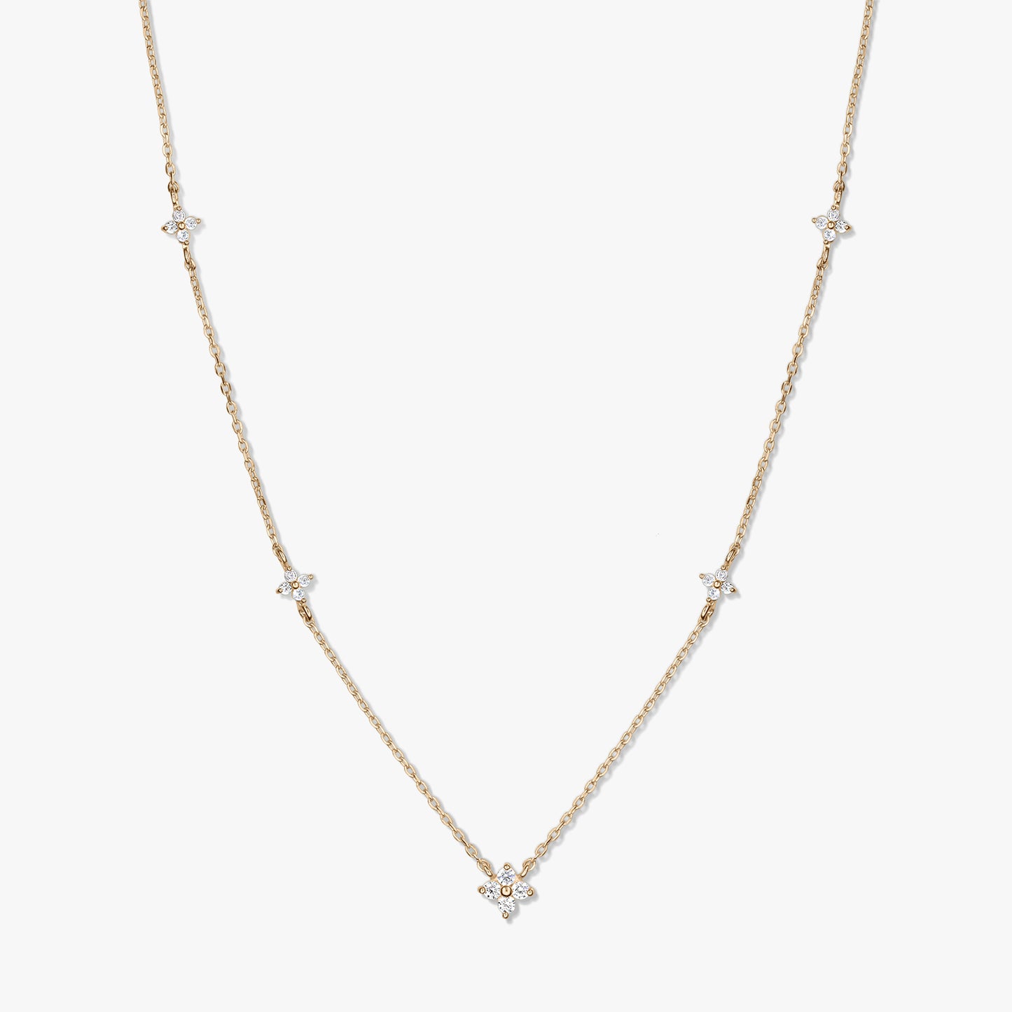 Collana a stazioni in oro giallo 14K con piccoli motivi a quadrifoglio in zirconia bianca su una catena sottile, fotografata su sfondo bianco.
