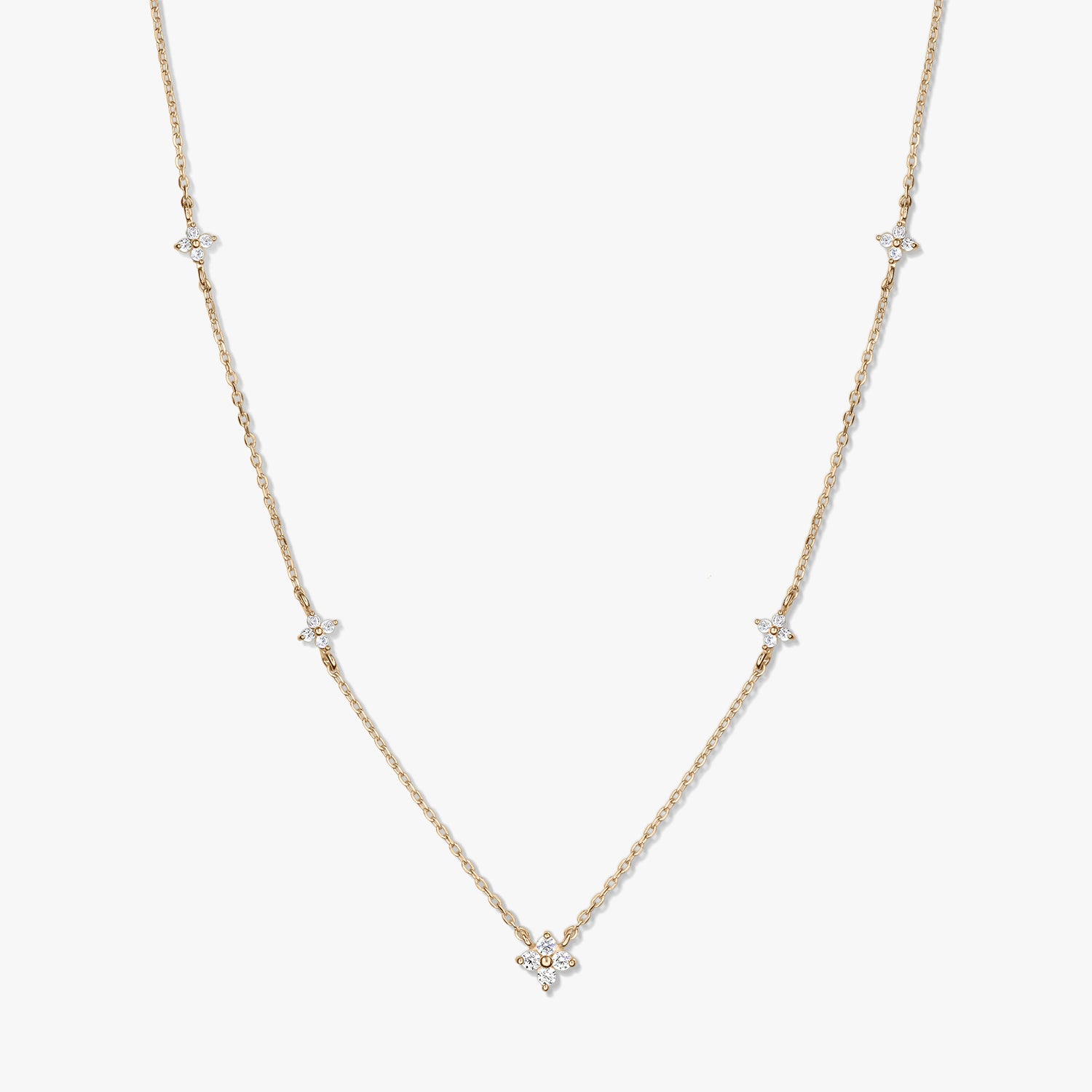 Collana a stazioni in oro giallo 14K con piccoli motivi a quadrifoglio in zirconia bianca su una catena sottile, fotografata su sfondo bianco.