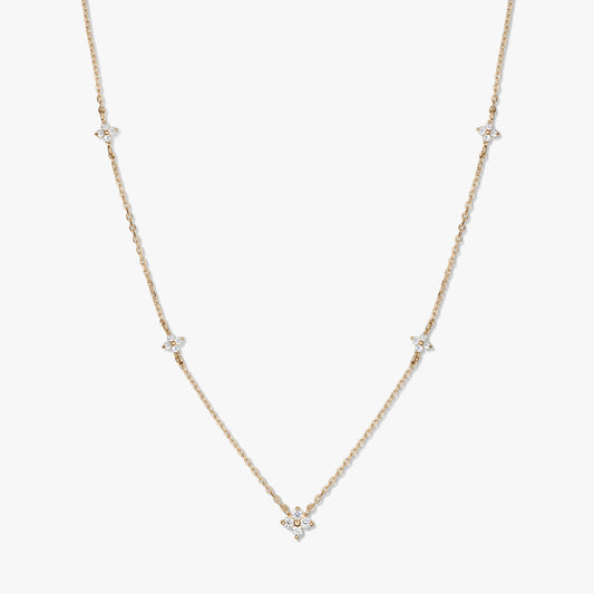 Collana a stazioni in oro giallo 14K con piccoli motivi a quadrifoglio in zirconia bianca su una catena sottile, fotografata su sfondo bianco.